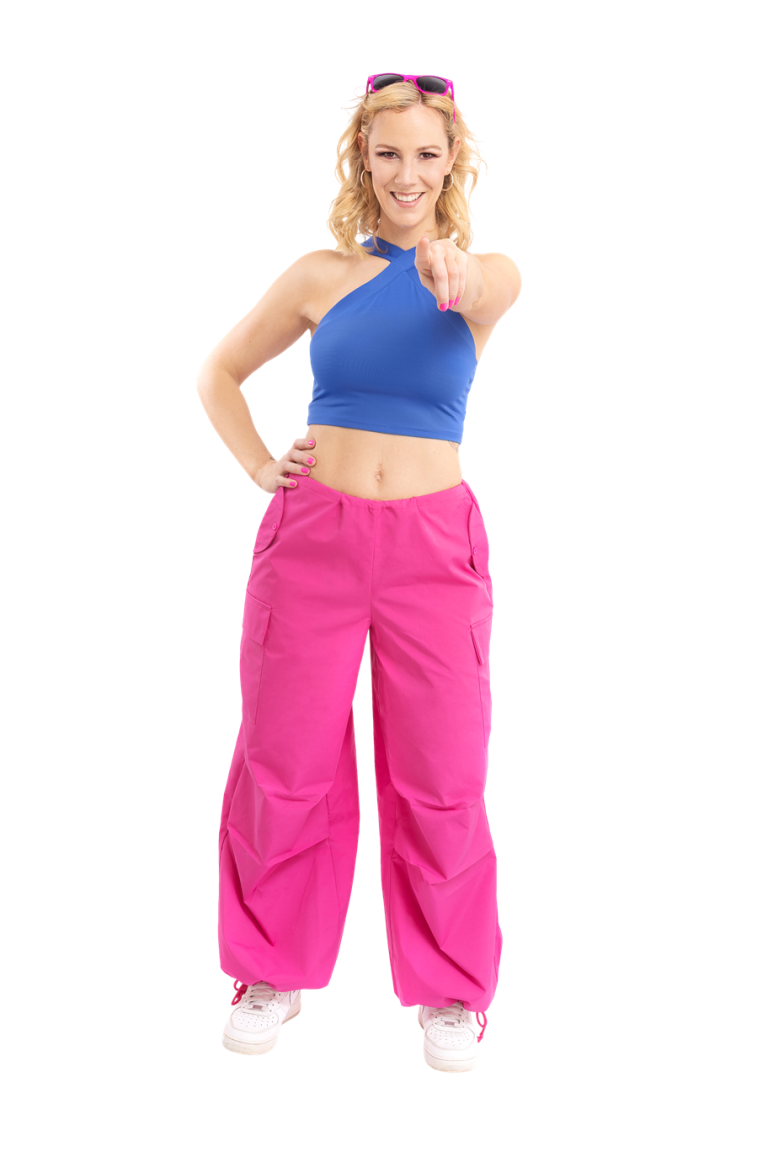 Milla Pink Milla Pink mit blauer Crop-Top und pinken weiten Hosen, zeigt mit dem Finger.